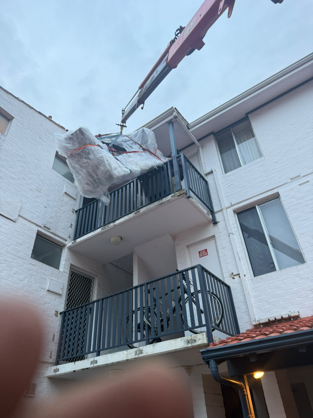 Crane lifting a sofa over a balcony, Perth